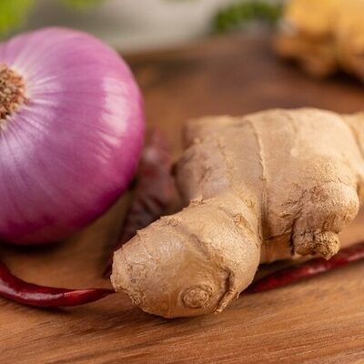 Fresh ginger, garlic cloves, and a sliced onion on a cutting board